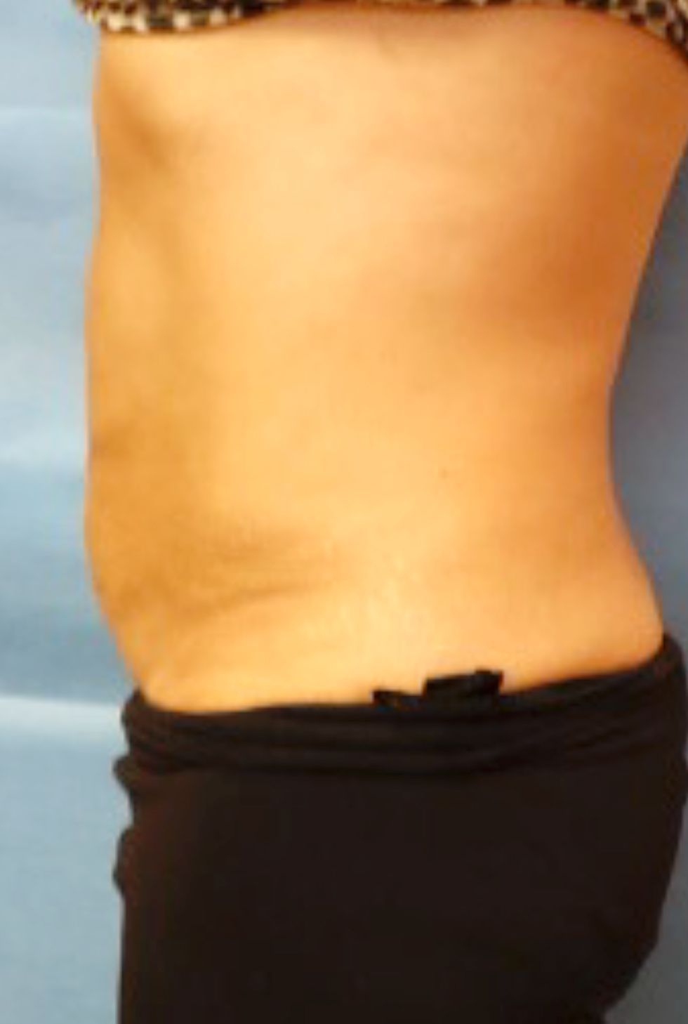 A woman without a shirt is standing in front of a blue cloth