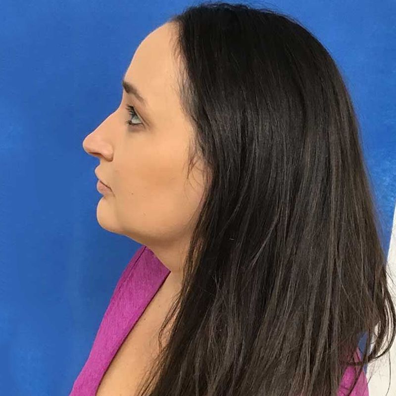 A woman with long dark hair is wearing a pink sweater