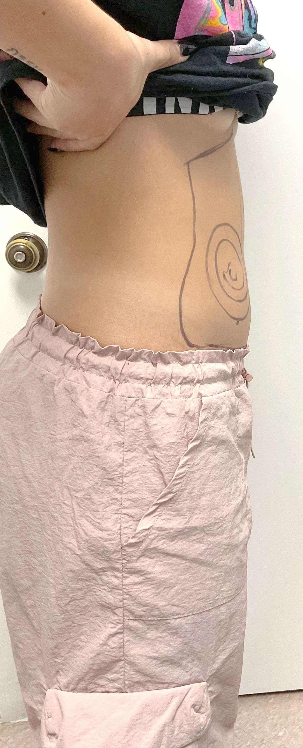 A woman without a shirt is standing in front of a door