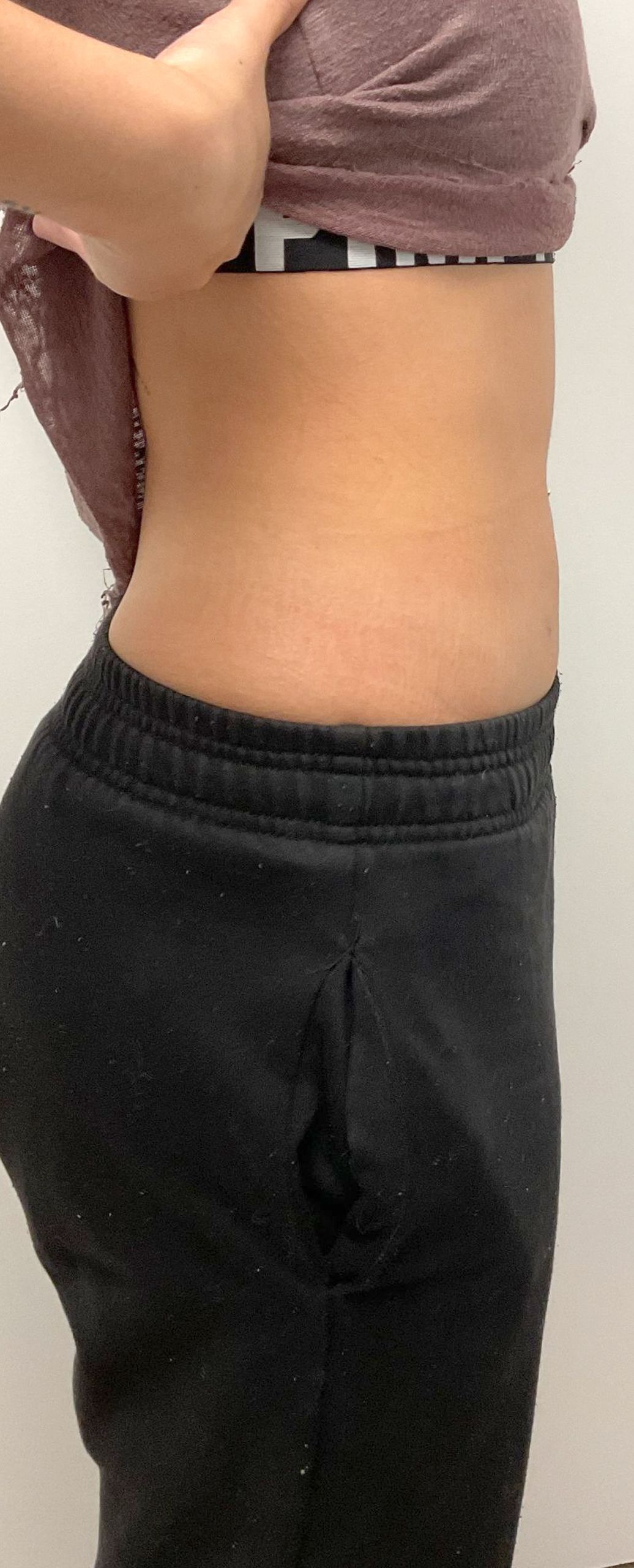 A woman is taking off her shirt and pants in a bathroom