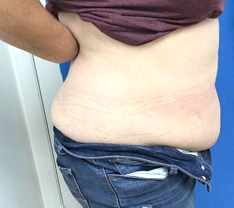 A woman with a large belly is standing in front of a blue door