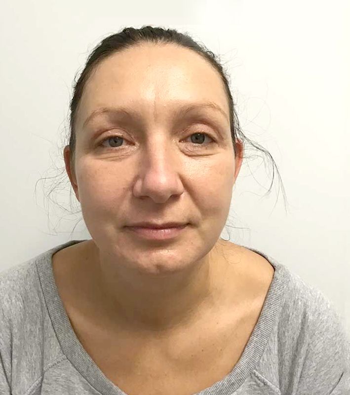 A woman in a grey shirt is looking at the camera