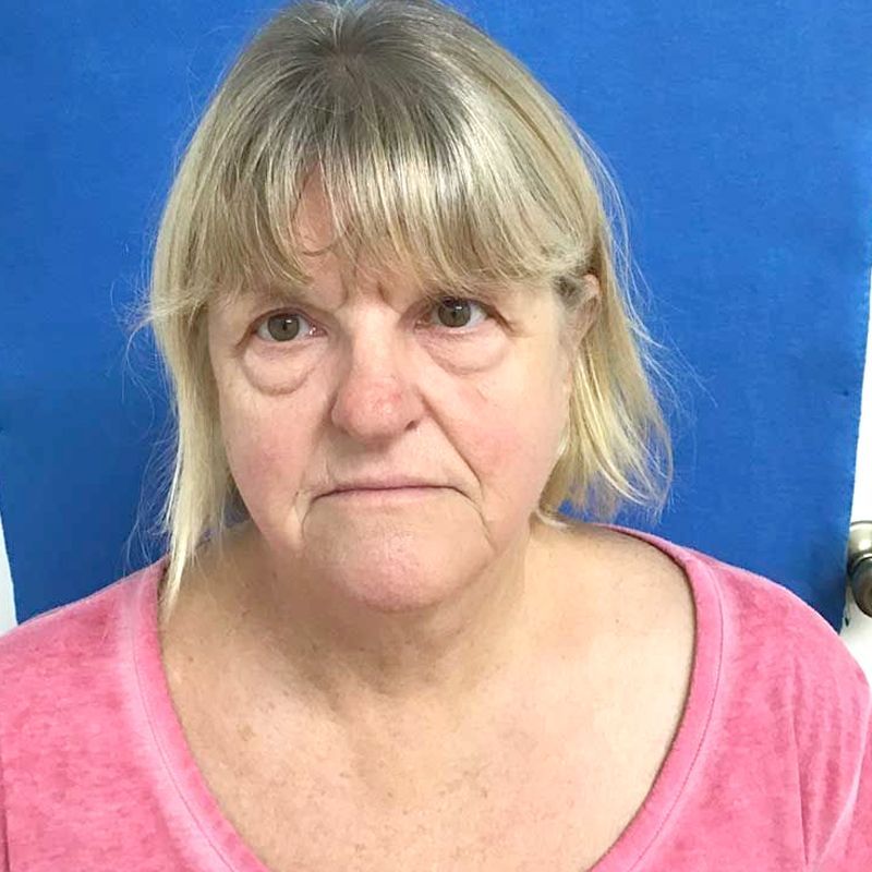 A woman in a pink shirt is looking at the camera