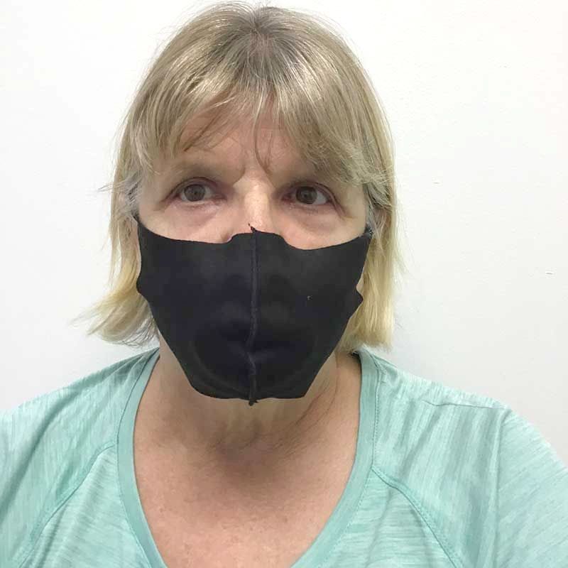 A woman wearing a black face mask and a green shirt