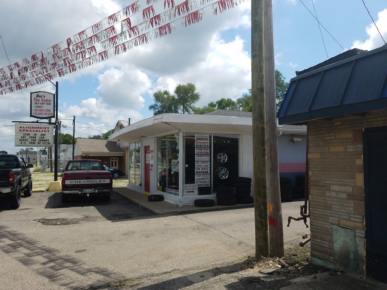 A red truck is parked in front of a car dealership