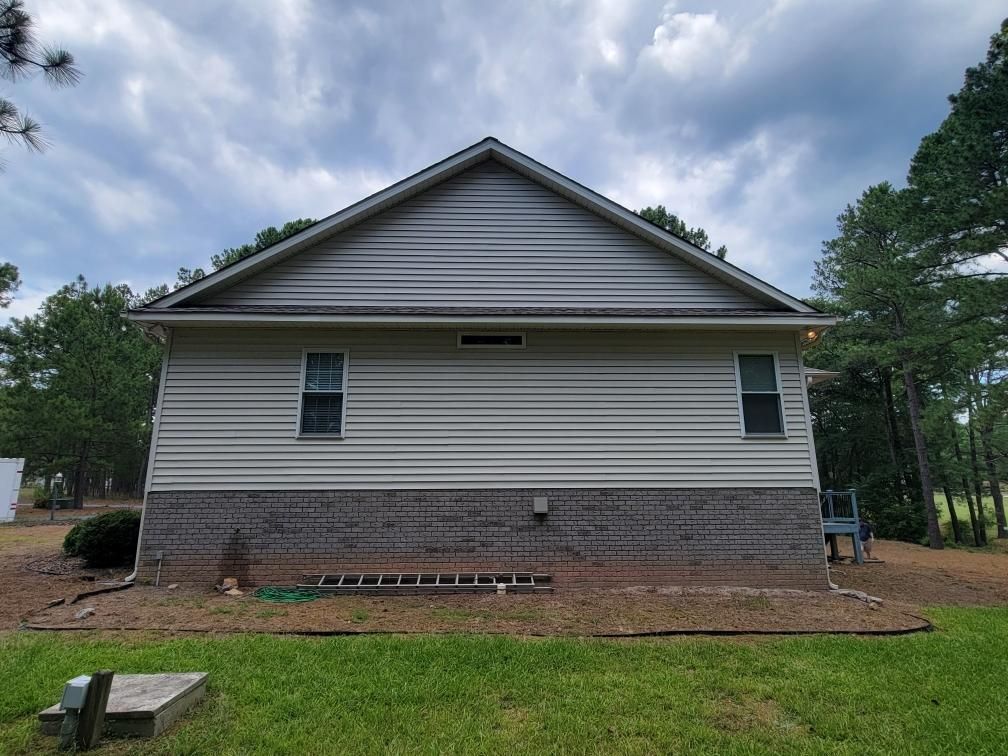 The back of a house with a ladder in the grass.