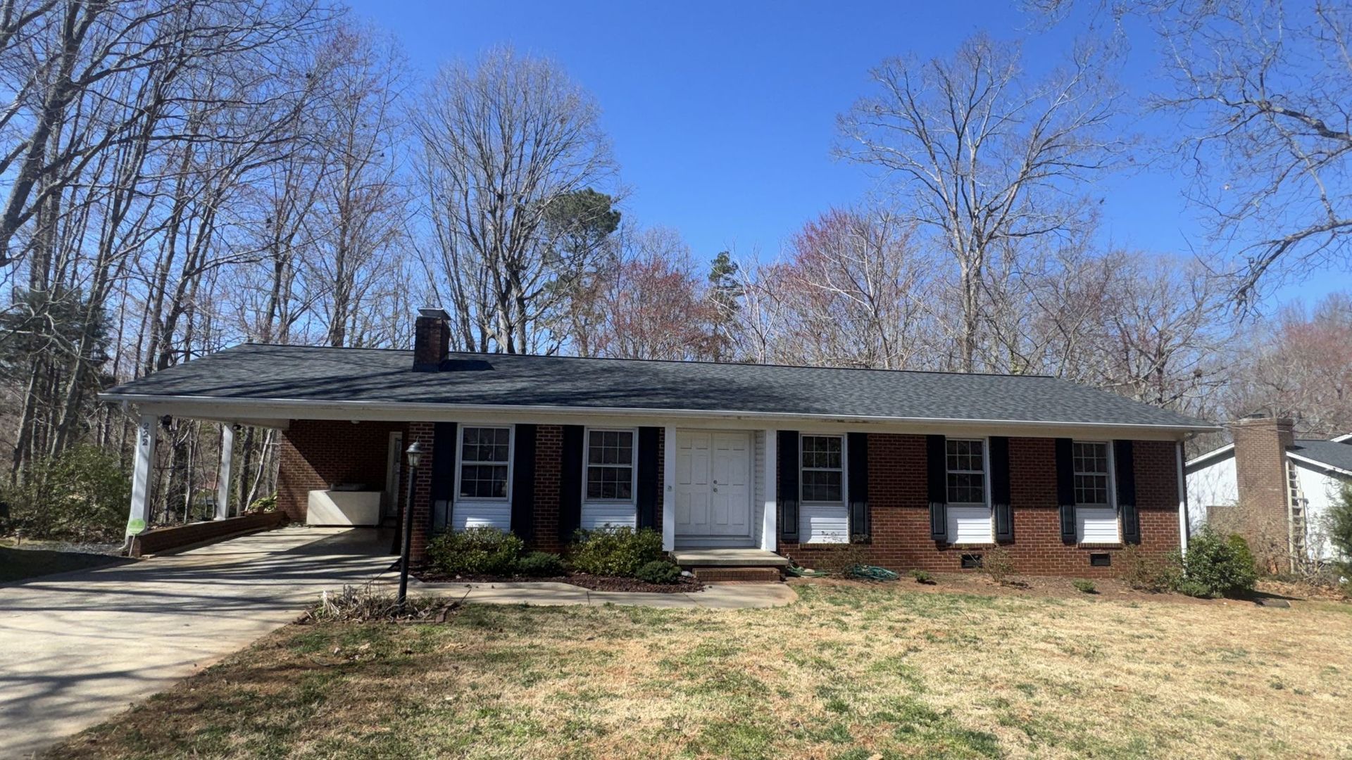A brick house with black shutters and a blue sky in the background.