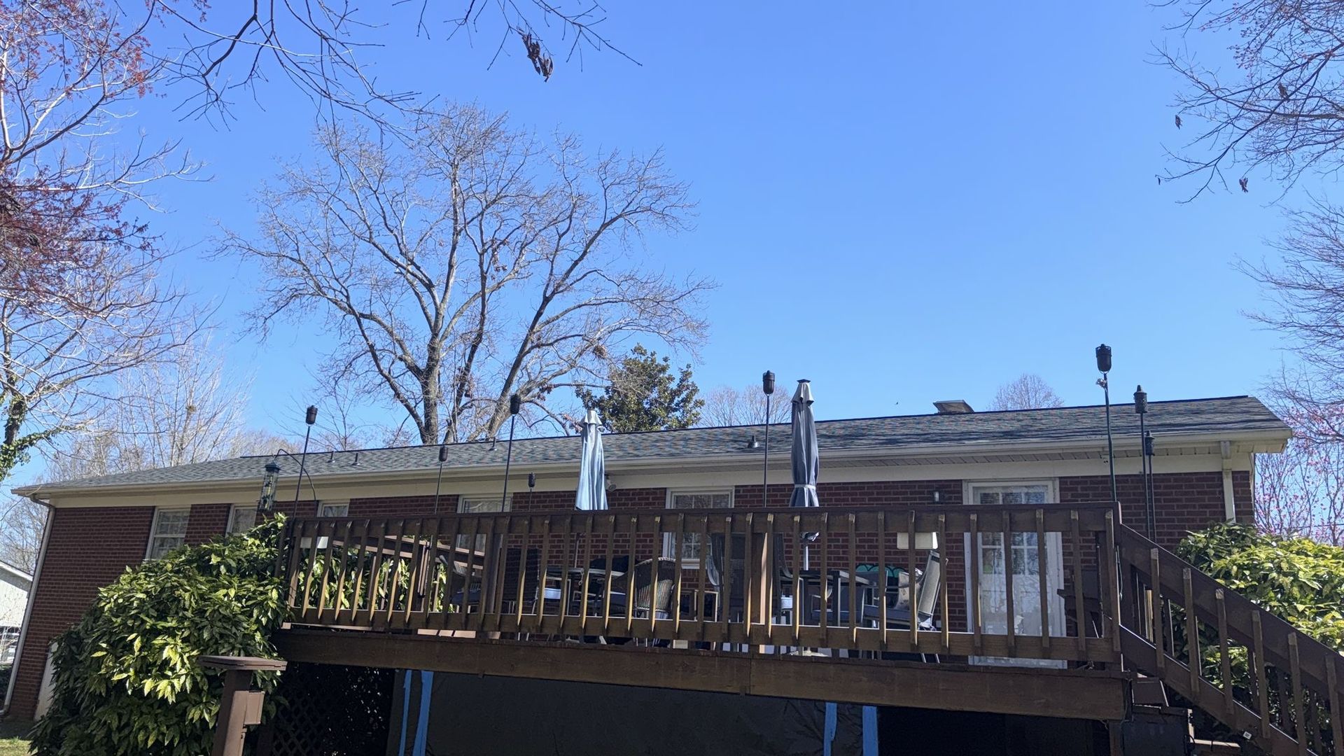 A house with a large deck and a blue sky in the background.