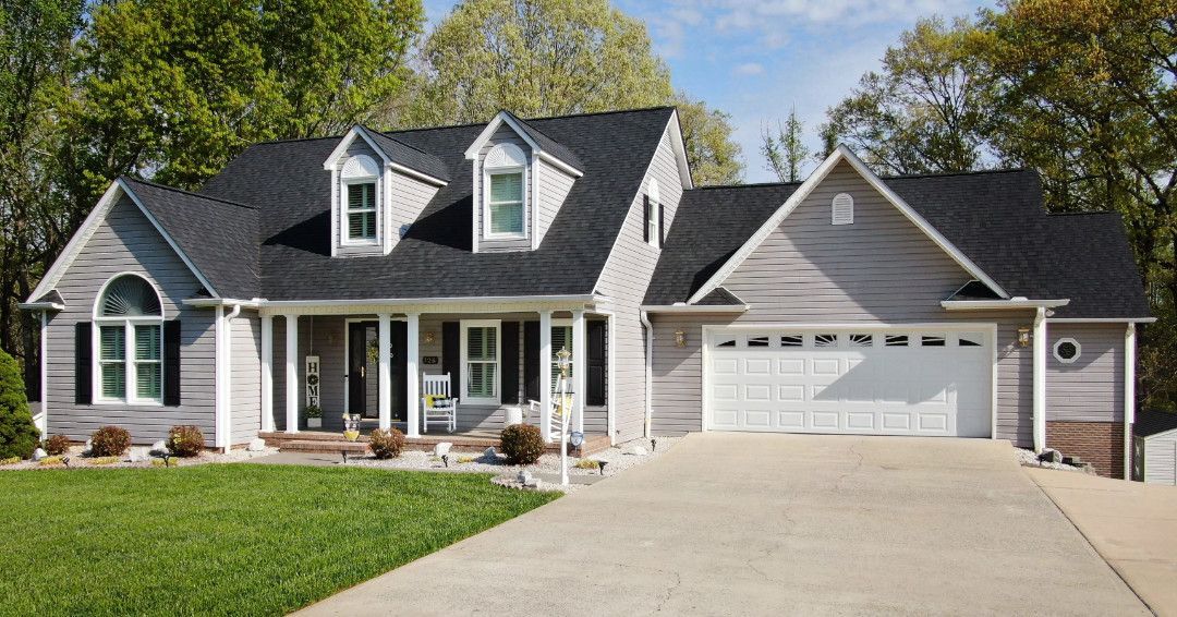 An aerial view of a large house with a gray roof surrounded by trees.