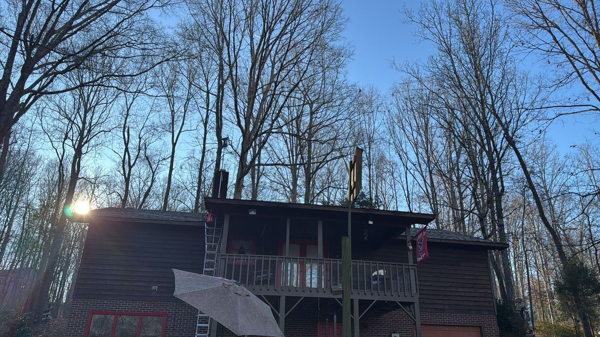 A large house with a large deck is surrounded by trees.