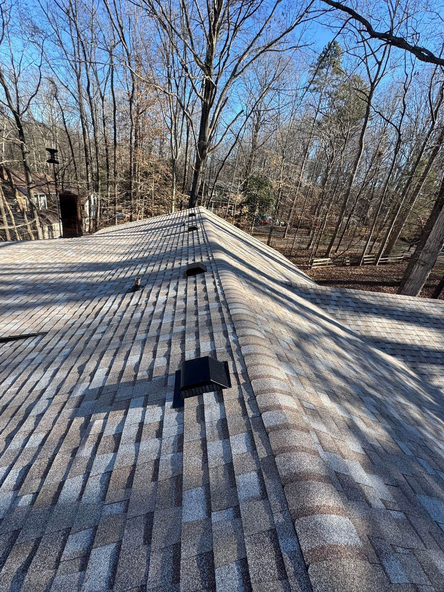 A roof with snow on it and trees in the background.
