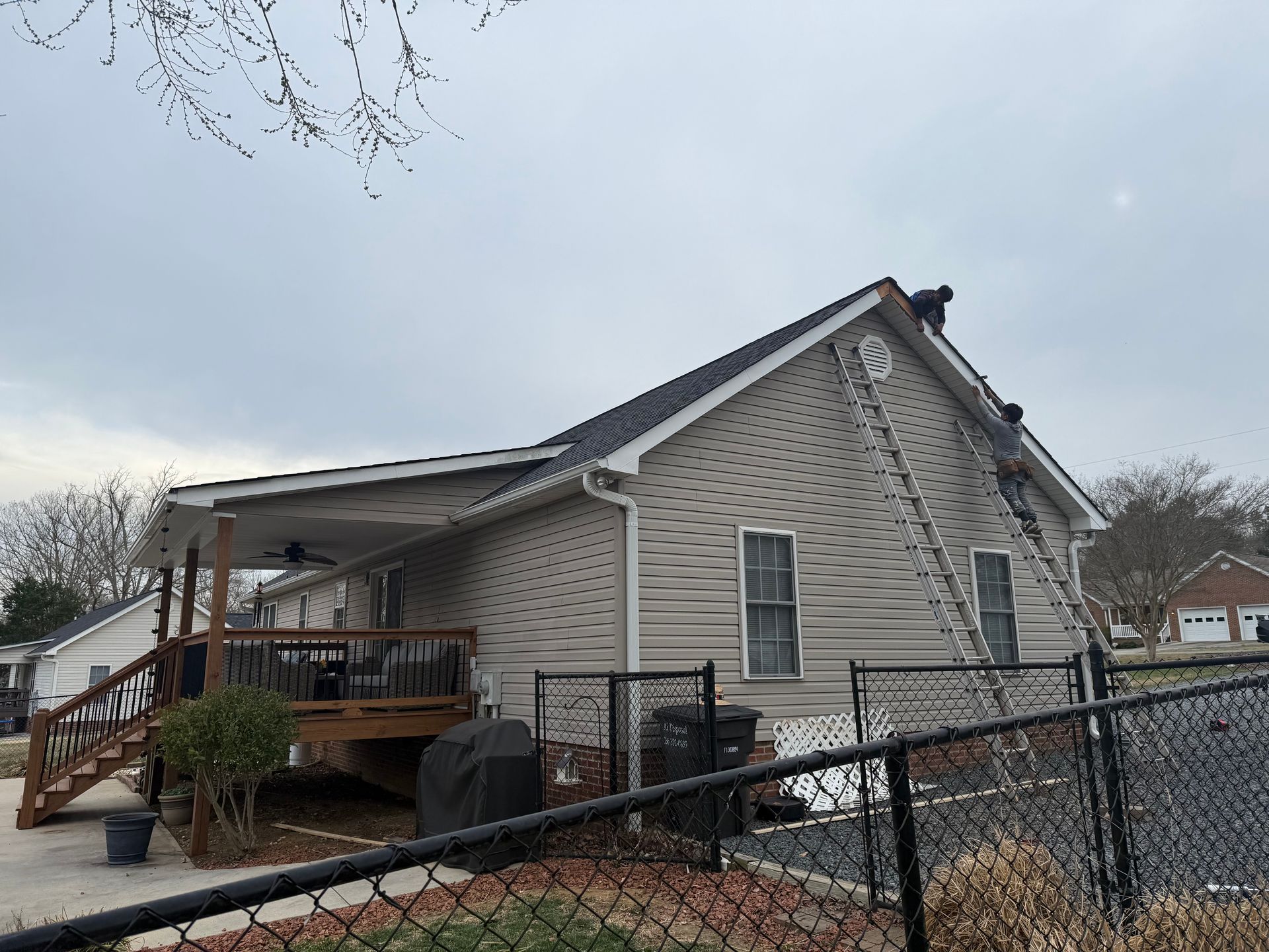 A man is painting the roof of a house with a ladder.