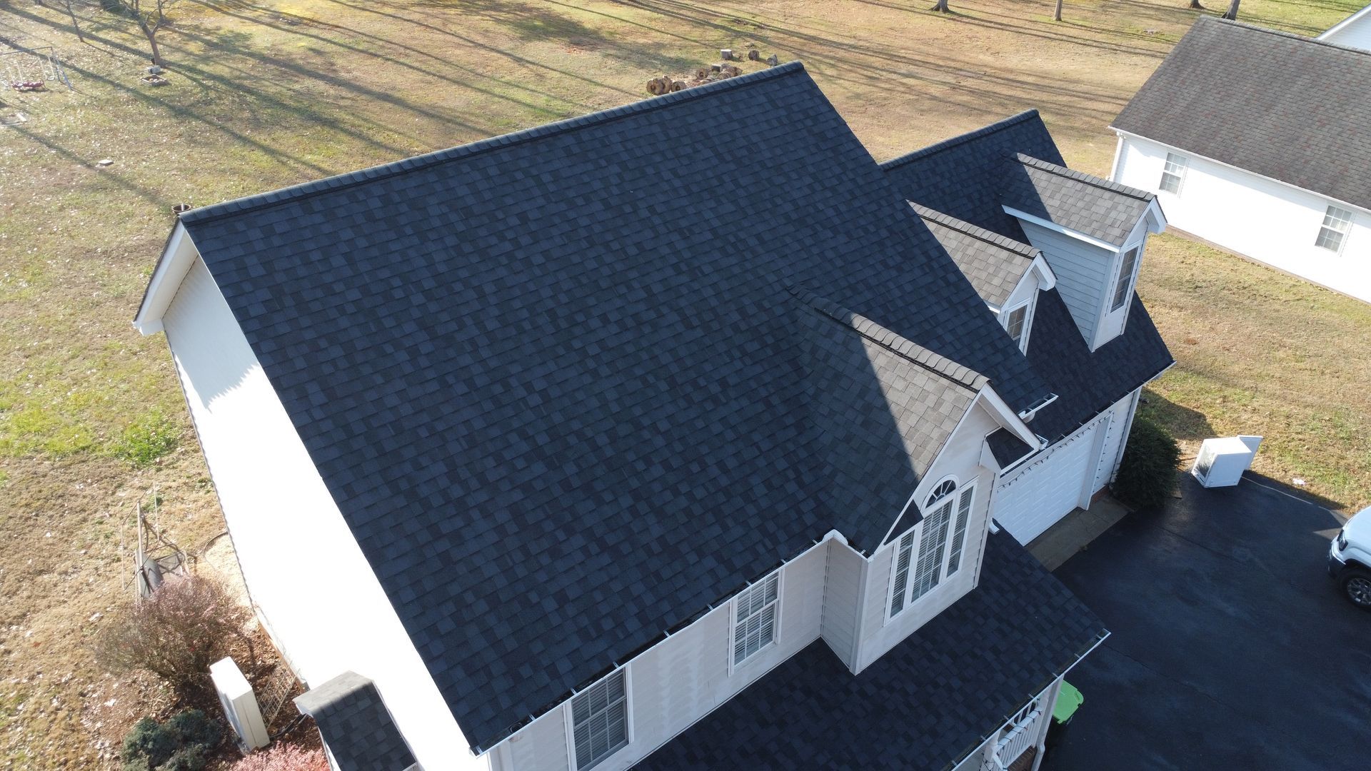 An aerial view of a white house with a black roof.