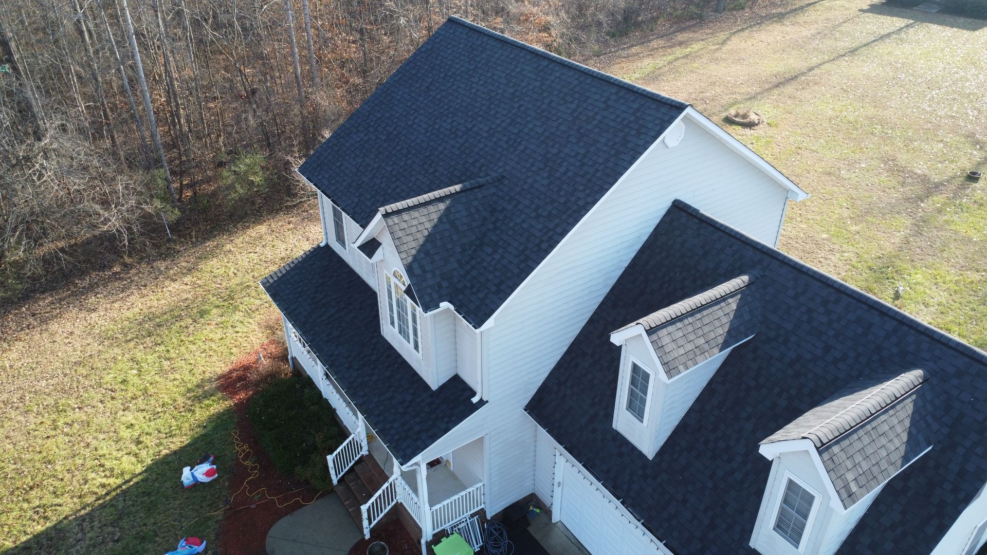 An aerial view of a white house with a black roof.