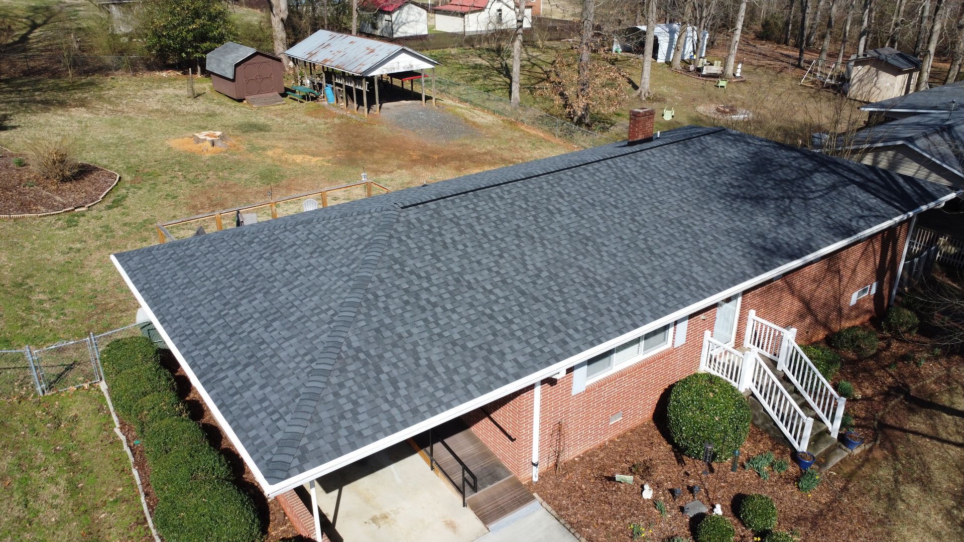An aerial view of a brick house with a new roof.