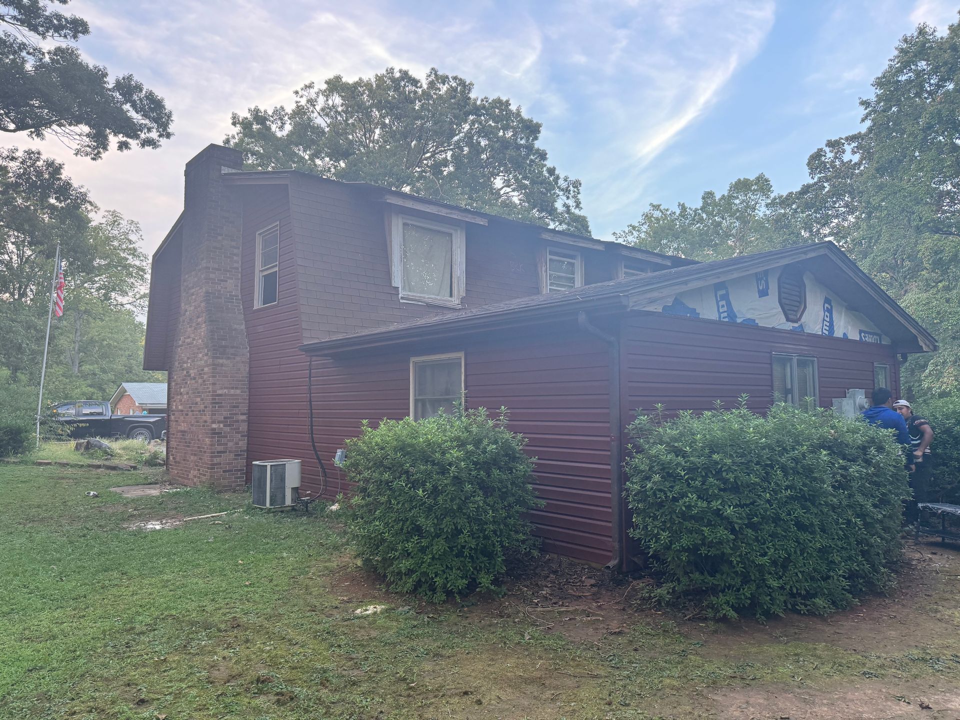 A large red brick house with a lot of bushes in front of it.