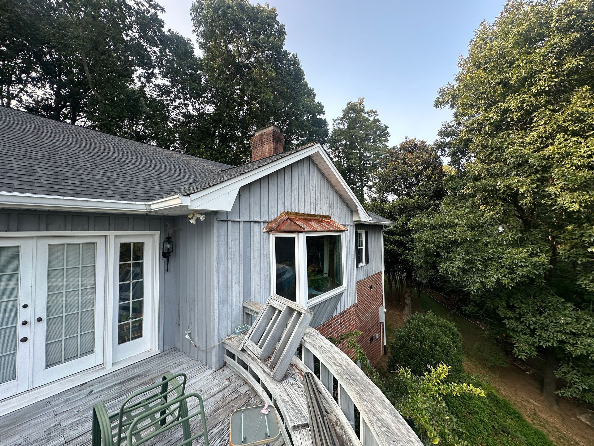 An aerial view of a house with a deck and trees in the background.