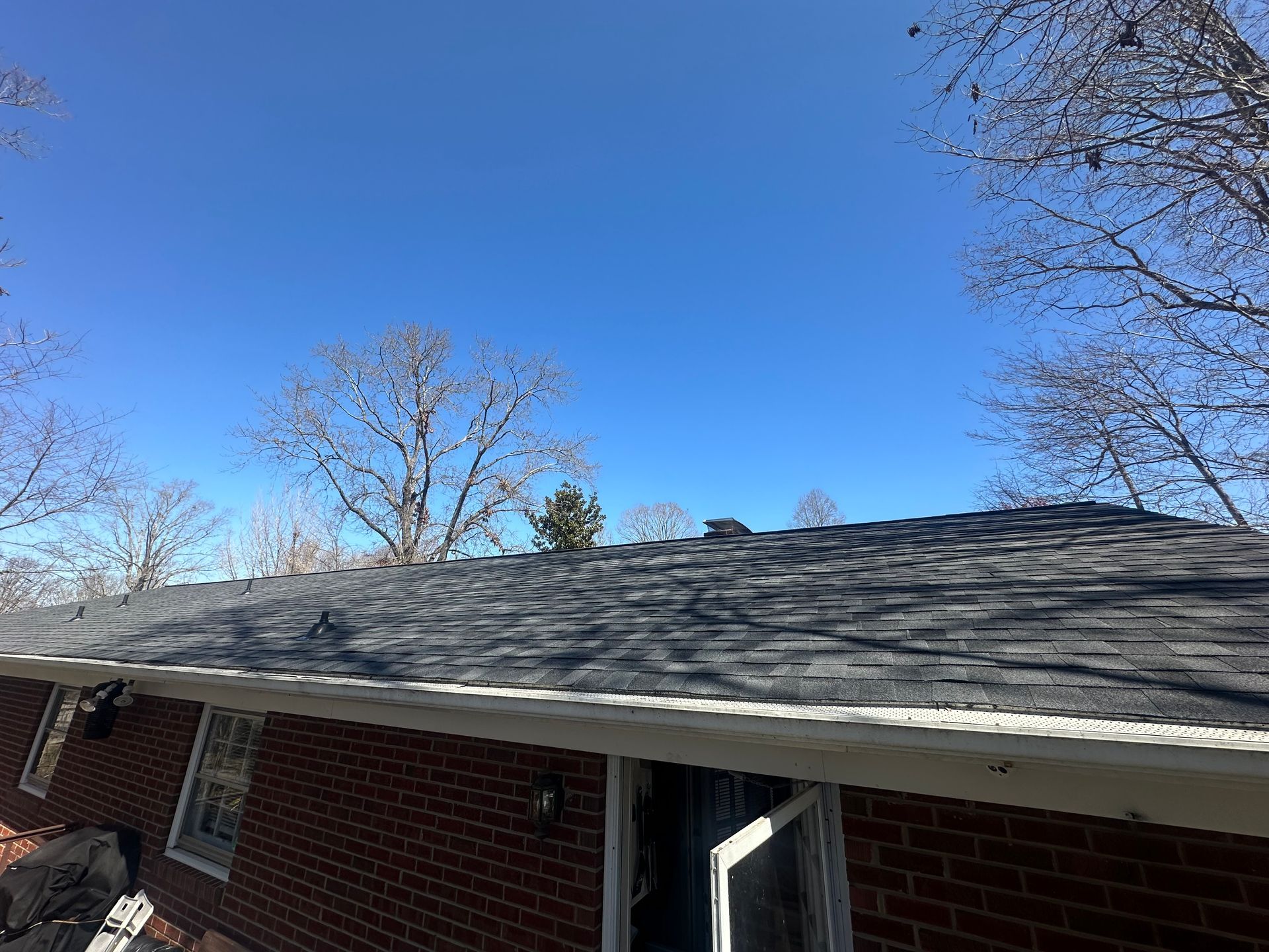 A brick house with a black roof and a blue sky in the background.