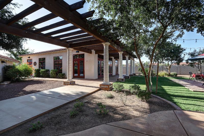 Courtyard with pergola, building with columns, and grassy area.