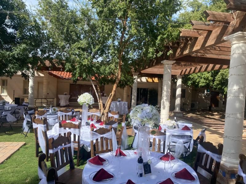 Outdoor wedding reception with round tables, white linens, and floral centerpieces.