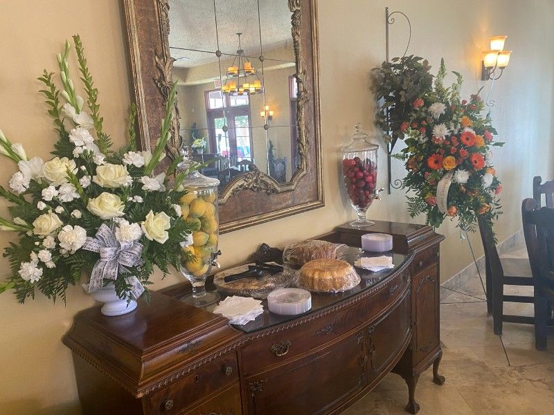 Buffet with flowers, desserts, and fruit jars. Ornate mirror above. Antique furniture. Restaurant interior.