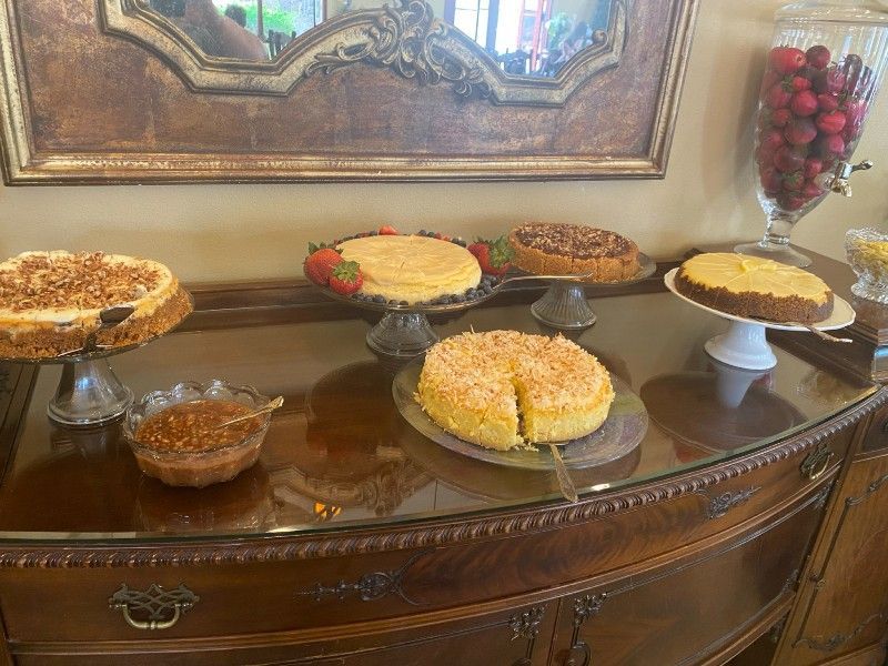 Cakes on display: Various flavors atop pedestals, arranged on a wooden sideboard, with a mirror above.