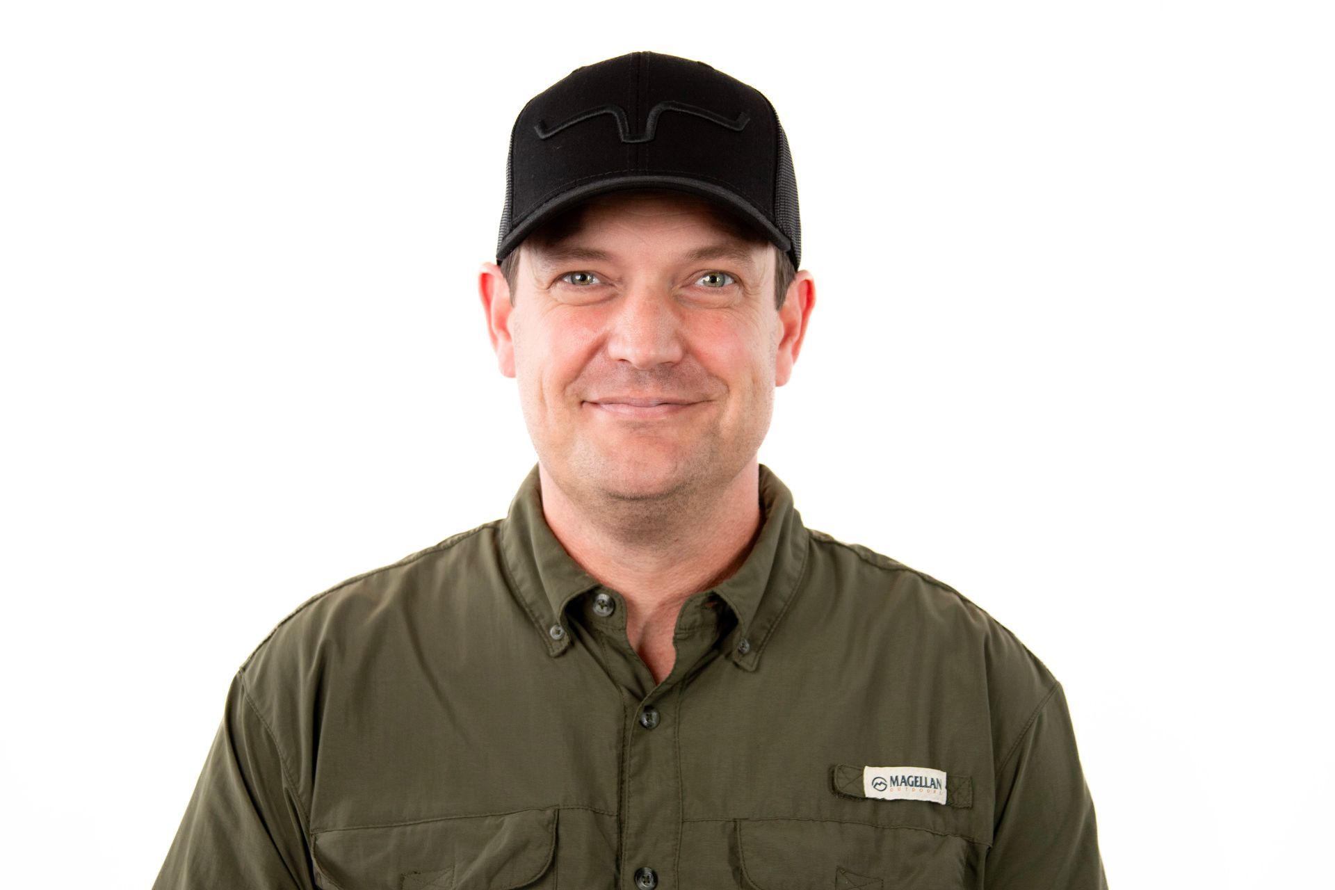 A man wearing a black hat and a green shirt is smiling.