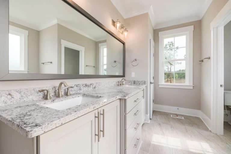 Bright modern bathroom with marble vanity, large mirror, and window under soft natural light