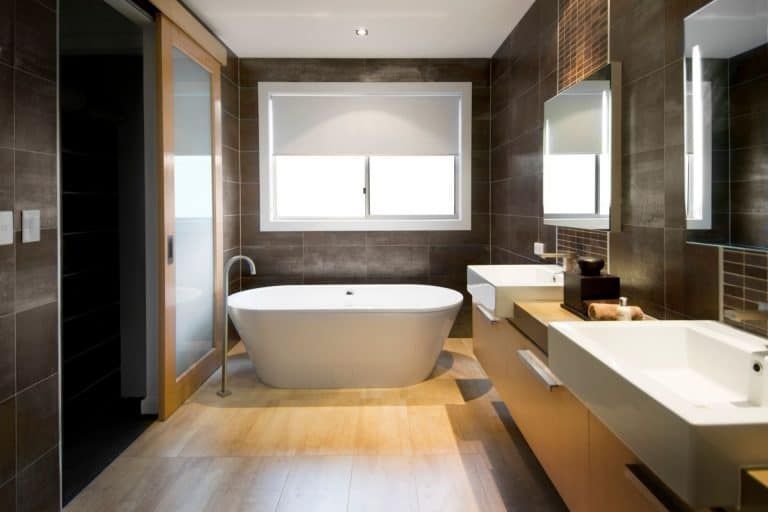 Modern bathroom with freestanding tub, double vanity, large mirror, and window