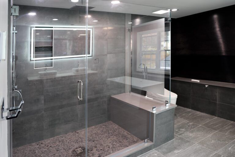 Modern glass-walled bathroom with shower, toilet, and gray tile flooring