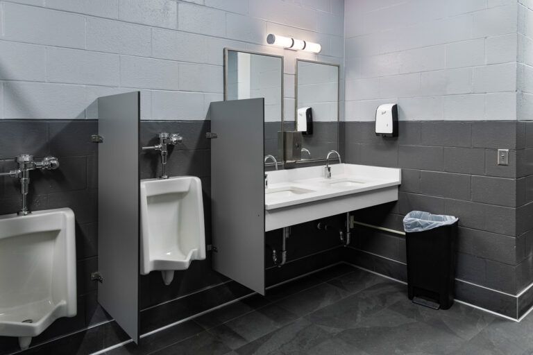 Public restroom with urinals, stall doors, sink, mirrors, and paper towel dispensers