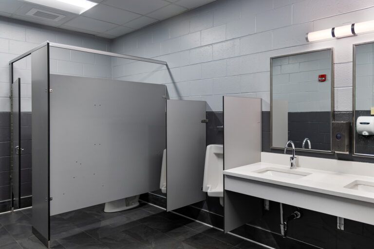 Public restroom with gray stalls, sinks, mirrors, and tiled walls