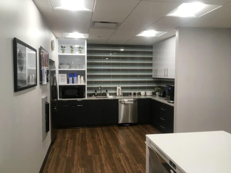 Modern kitchen with black cabinets, stainless dishwasher, and wood flooring