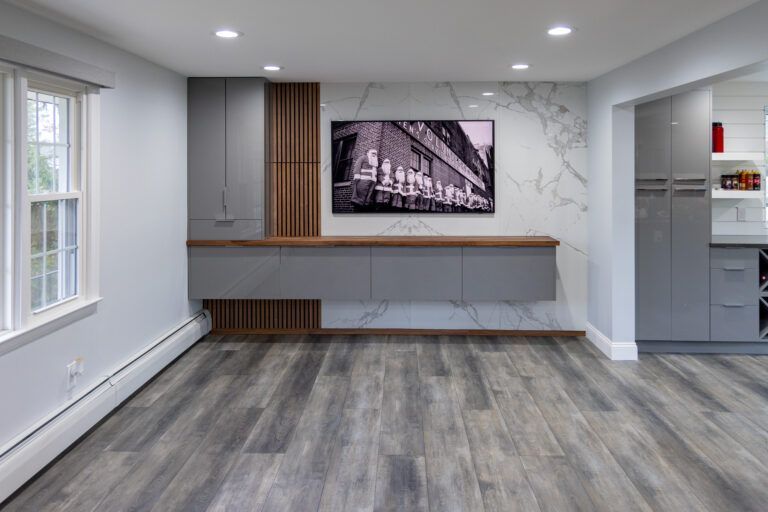 Empty modern room with gray floors, built-in cabinets, and a wall-mounted TV above a desk area