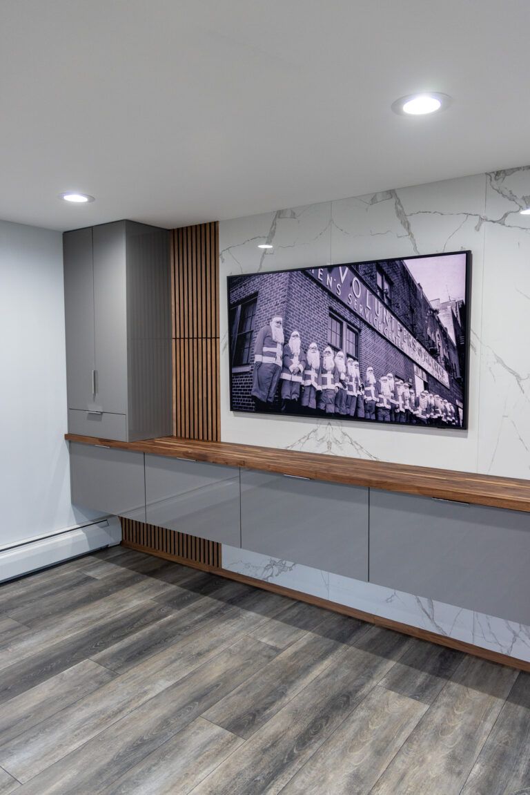 Modern office lobby with gray walls, wood accents, and a large black-and-white wall-mounted TV