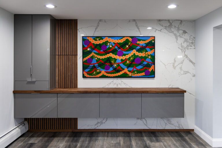 Modern room with gray cabinets, wood accents, marble walls, and a colorful abstract painting