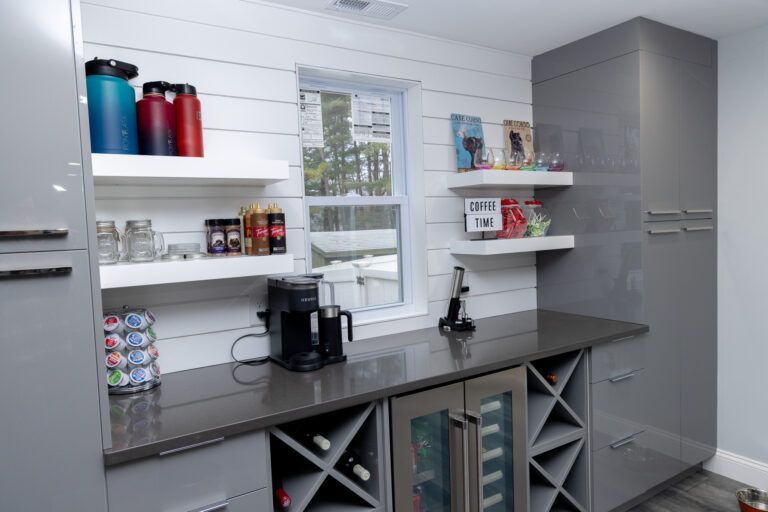 Modern kitchen coffee station with gray counters, white shelves, and red storage containers