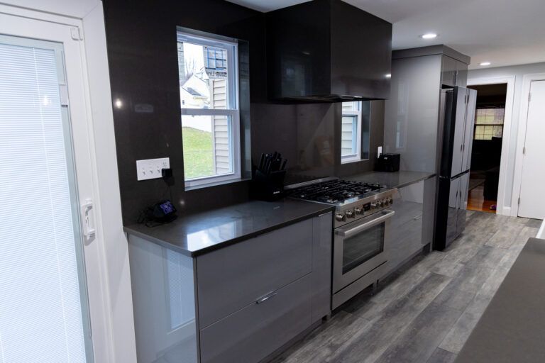 Modern kitchen with dark cabinets, stainless appliances, gray counters, and wood-look flooring