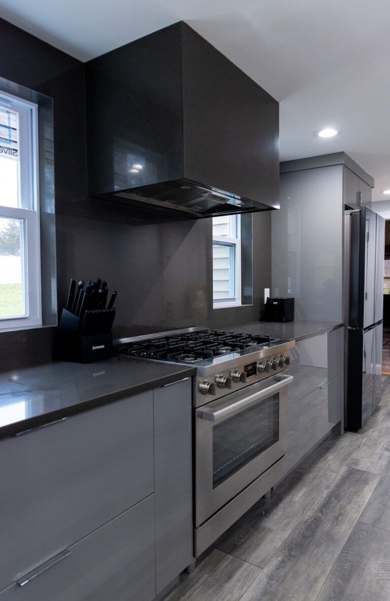 Modern kitchen with dark cabinets, stainless steel appliances, and a black countertop