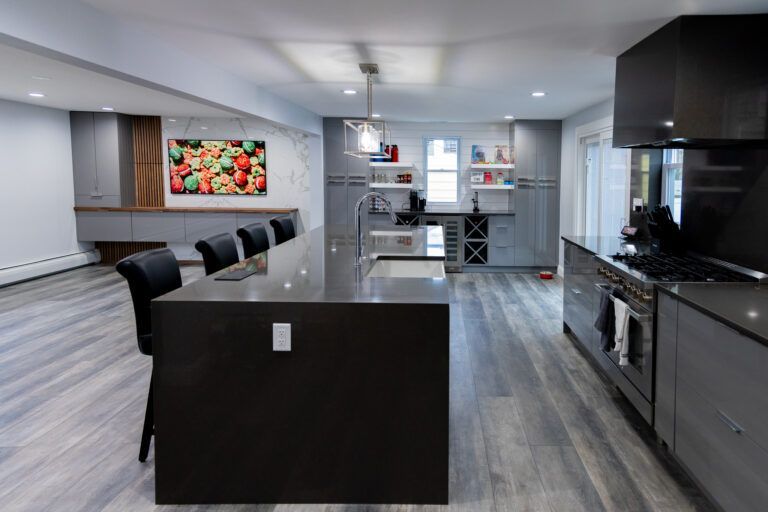 Modern open-concept kitchen with dark island, gray cabinets, stainless appliances, and wood-look floors