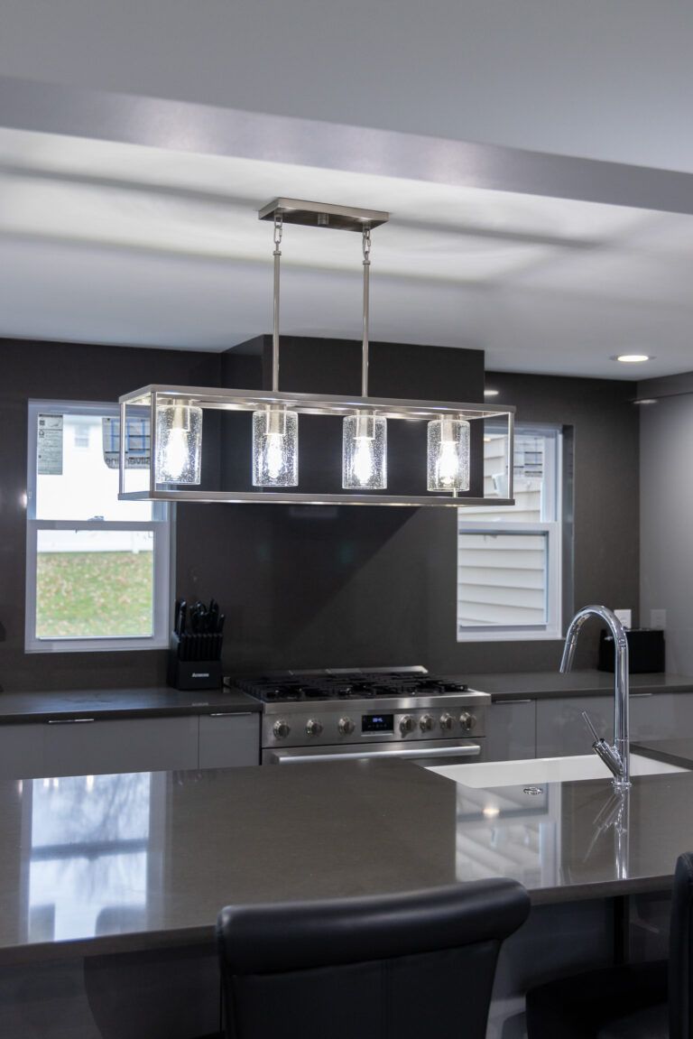 Modern kitchen with island, pendant light, stainless appliances, and gray walls