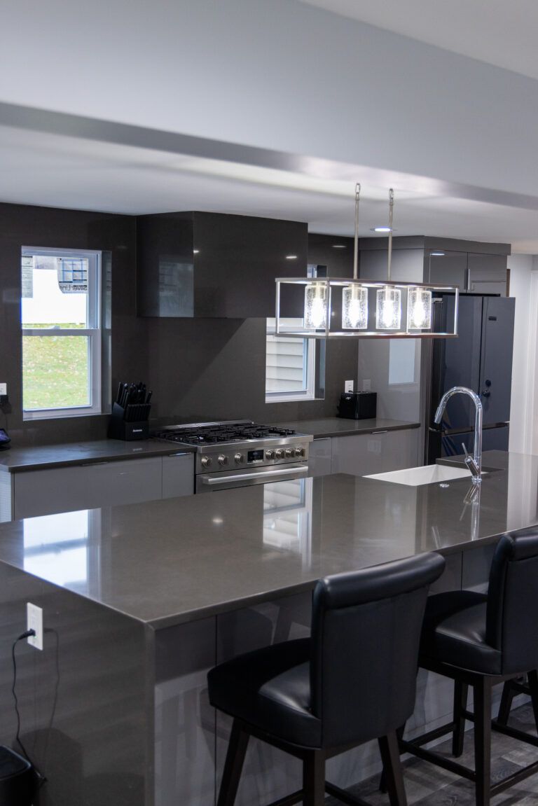 Modern kitchen with a large island, black stools, pendant lights, and stainless steel appliances