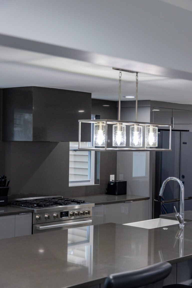 Modern kitchen with dark cabinets, island, chrome pendant lights, and stainless steel appliances
