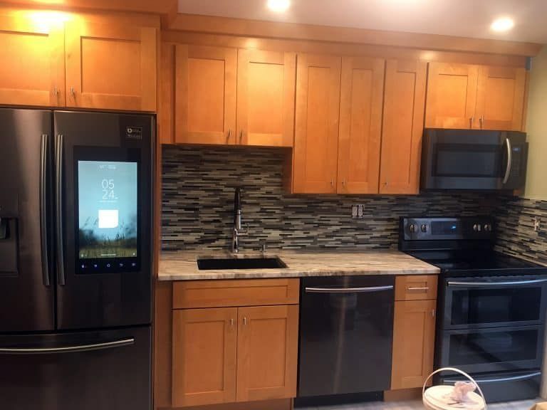 Modern kitchen with wood cabinets, black appliances, and stone backsplash
