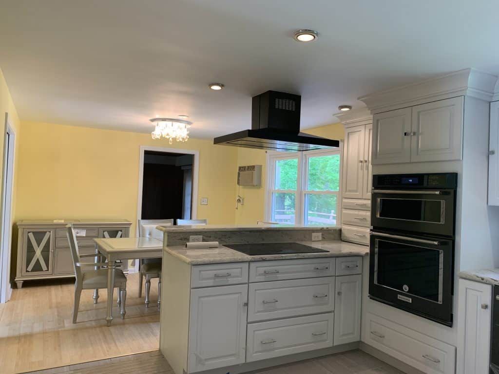 Bright white kitchen with gray island, dining area, and yellow walls