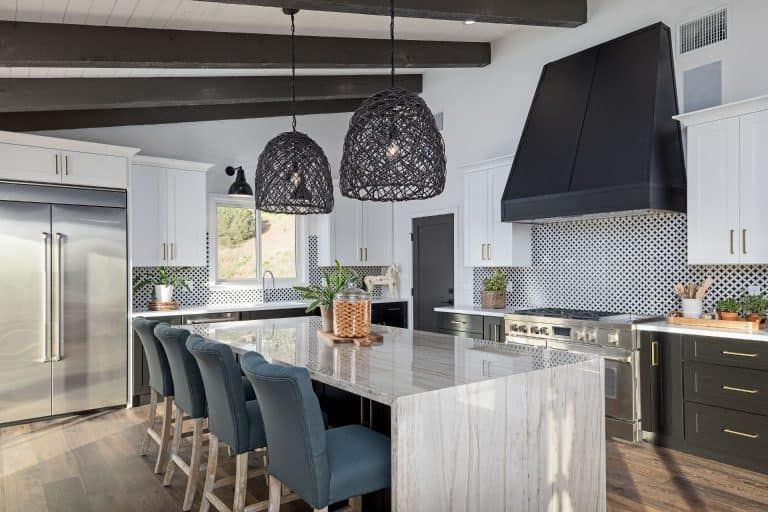 Modern kitchen with dark pendant lights, large island, bar stools, and stainless steel appliances