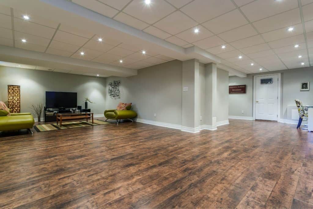 Empty community room with wood floors, white walls, recessed lighting, and a few chairs along the back wall