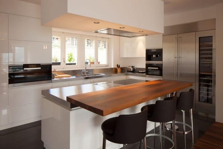 Modern kitchen with white cabinets, stainless appliances, and a wooden island with bar stools