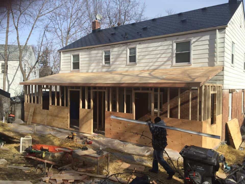House under construction with wooden framing and workers in the yard