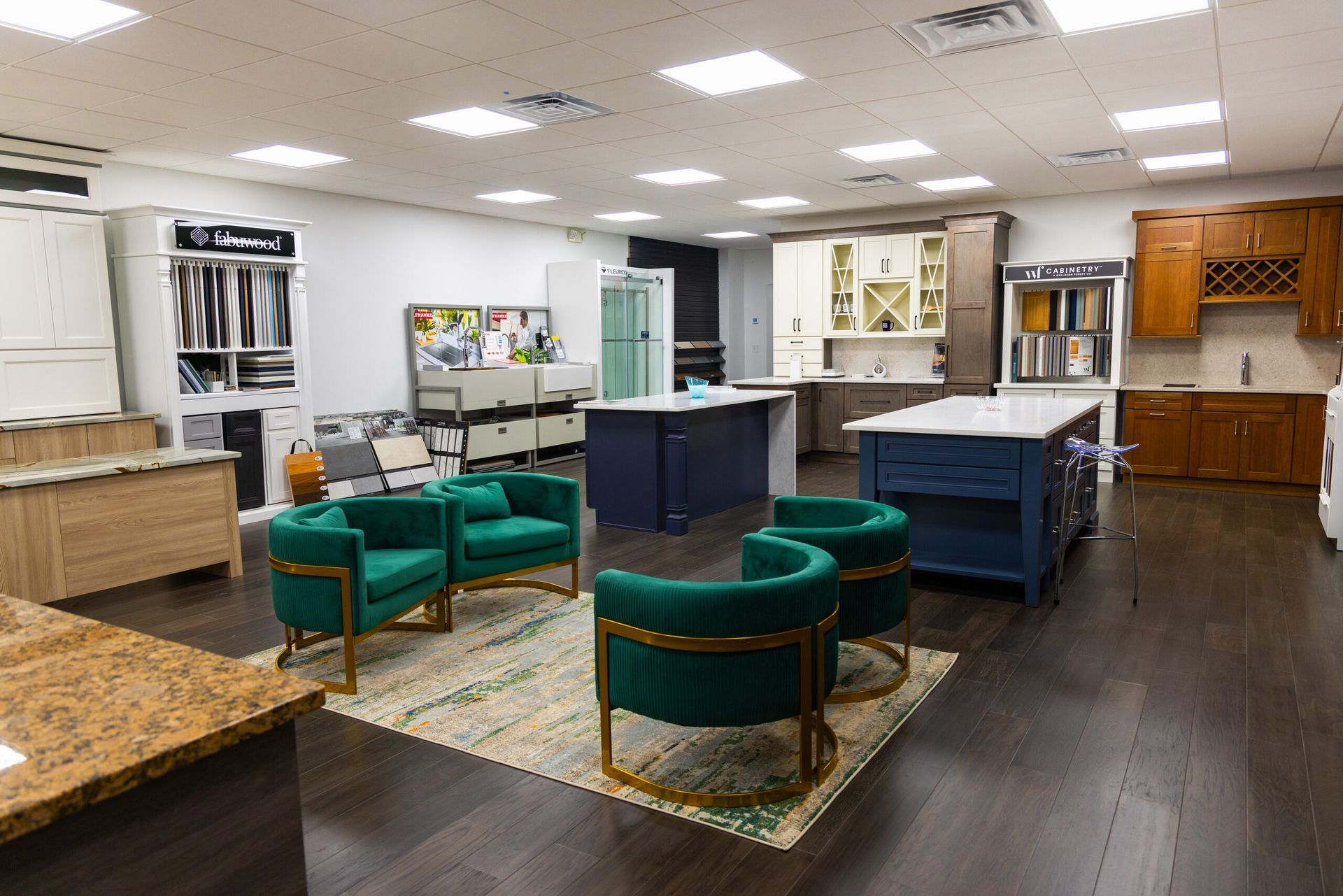 Bright showroom with green chairs, blue tables, and wooden cabinets under fluorescent lights.
